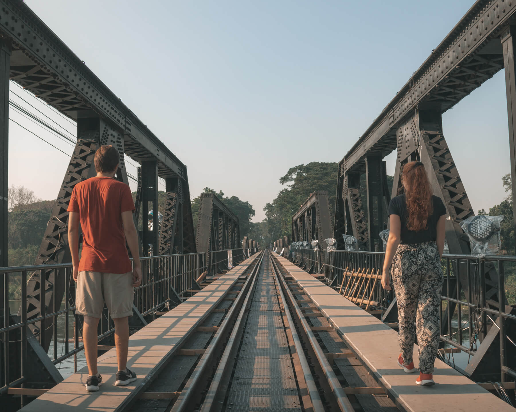 Couple walking across bridge over the River Kwai, Kanchanaburi, Thailand